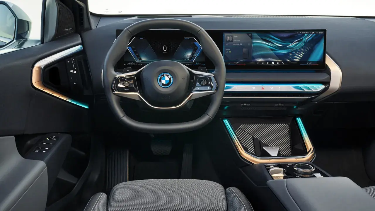 Interni moderni con volante, cruscotto digitale e ampio schermo per il sistema infotainment. Dettagli luminosi e finiture eleganti.