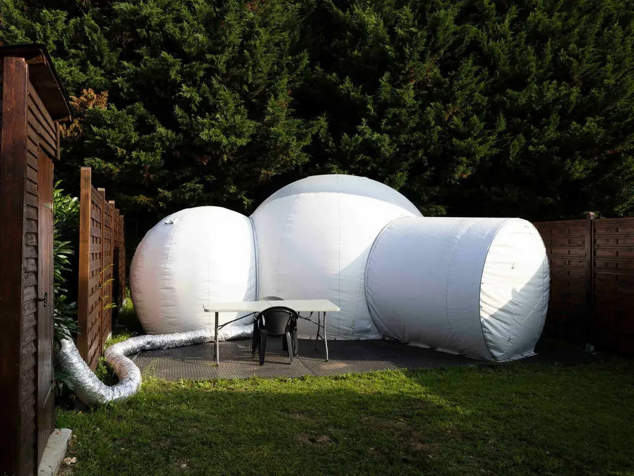Une bulle gonflable blanche, prête pour une nuit insolite en Île-de-France, est installée dans un jardin verdoyant.