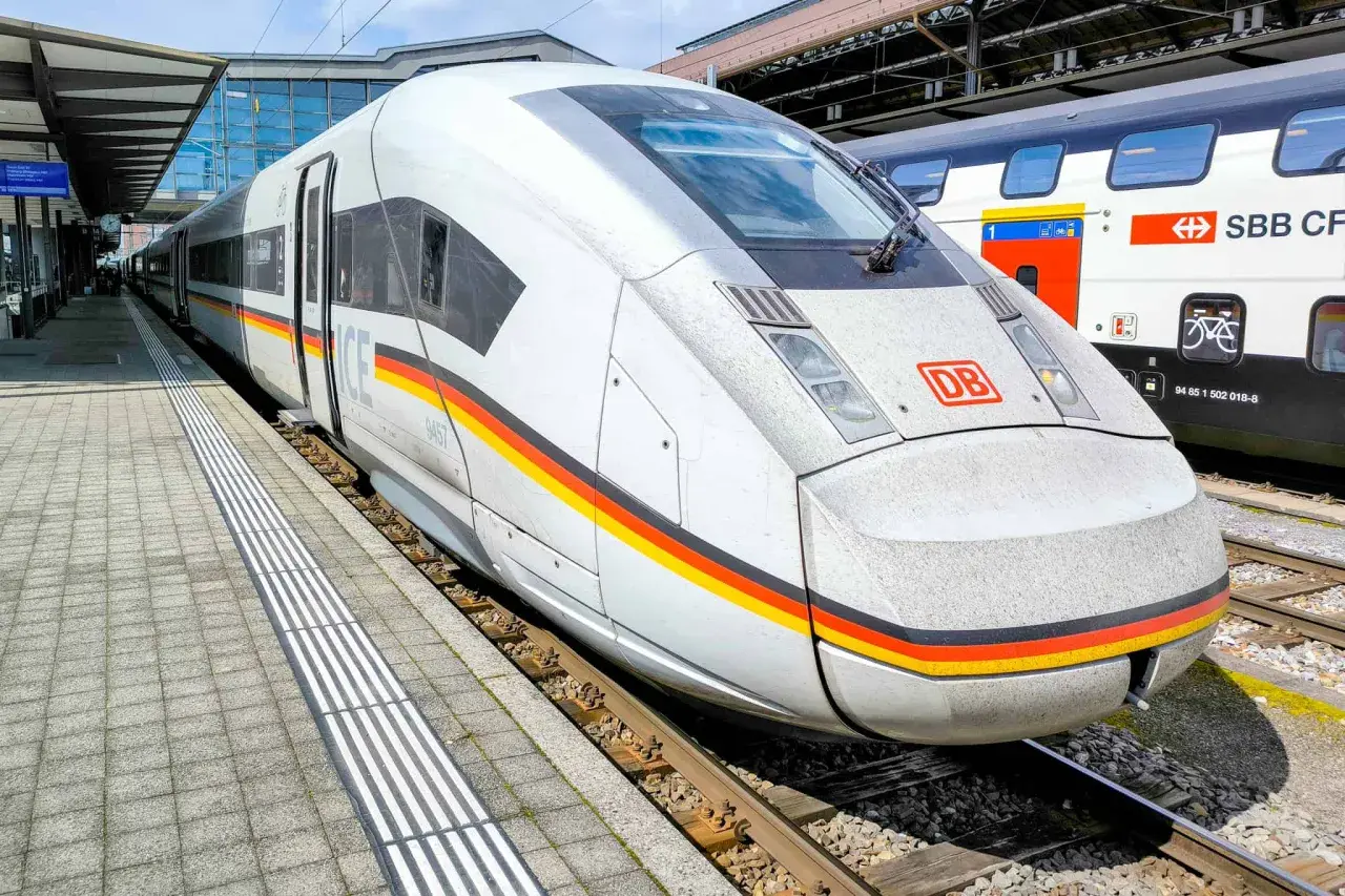 Moderner ICE train mit Deutschlandfarben am Bahnhof. Daneben ein SBB CFF FFS Zug.