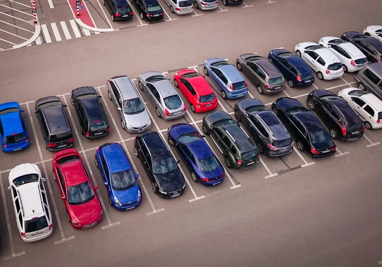 Wspólnota mieszkaniowa pilnuje porządku, by uniknąć mandatu za parkowanie. Wiele samochodów na parkingu.