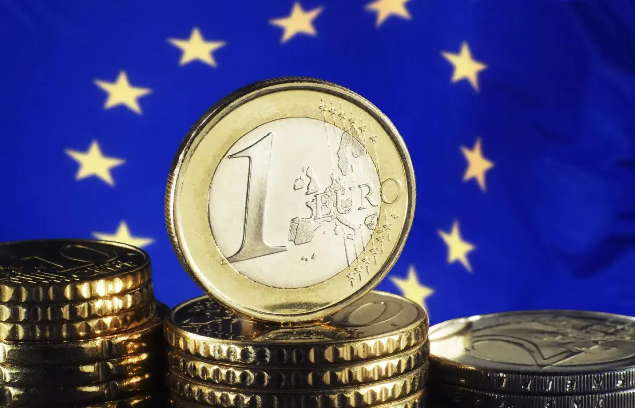 Monety euro na tle flagi UE. Pamiętasz, w którym roku weszło euro w Niemczech?