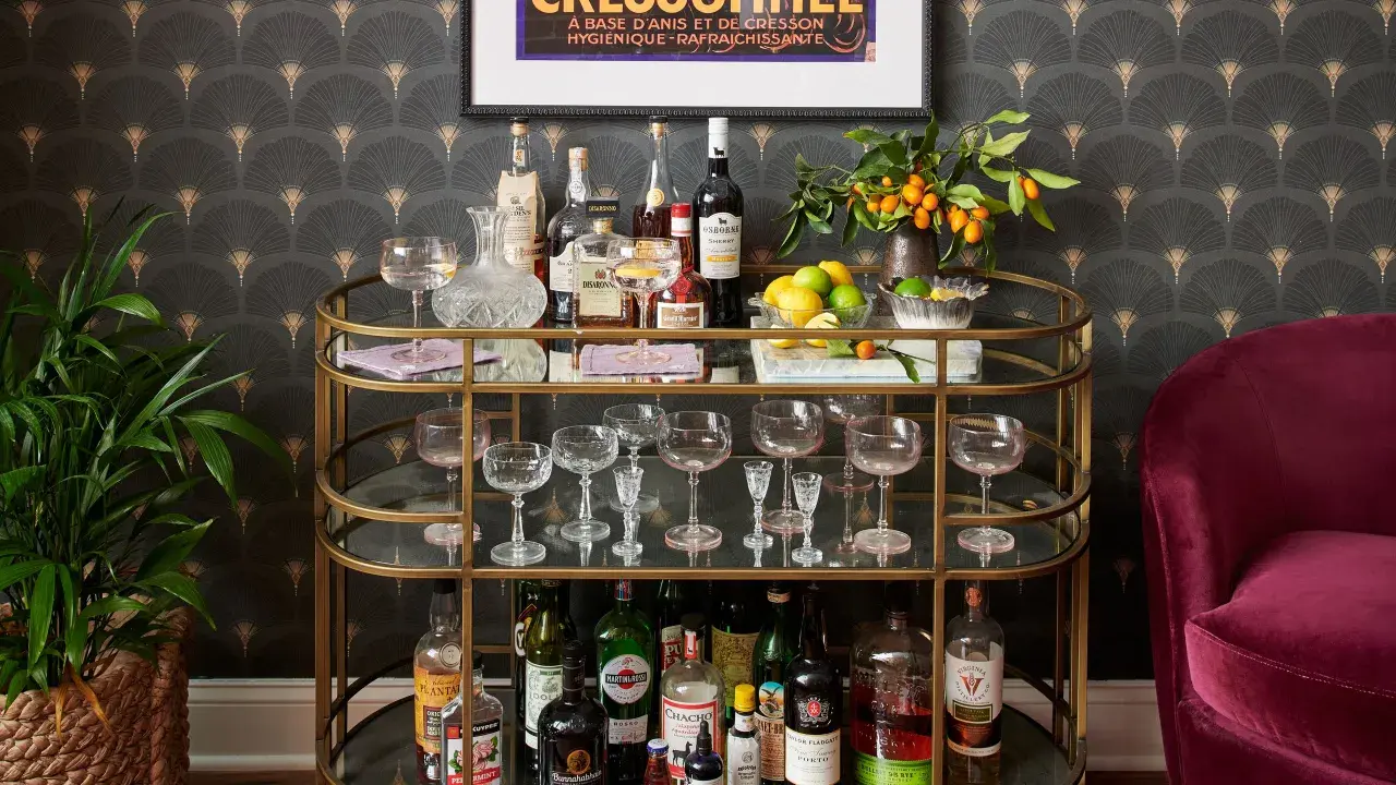 A stylish bar cart with bottles, glassware, lemons, and kumquats, offering inspiration on how to style a bar cart for a sophisticated home bar.