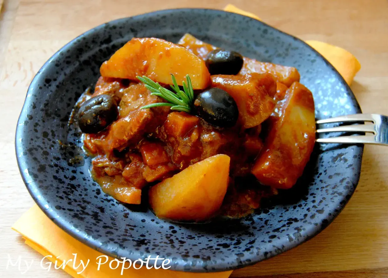 Un plat appétissant de sauté de veau à la tomate, garni d'olives noires et de romarin. Quel vin avec sauté de veau à la tomate ? Un rouge léger serait parfait.