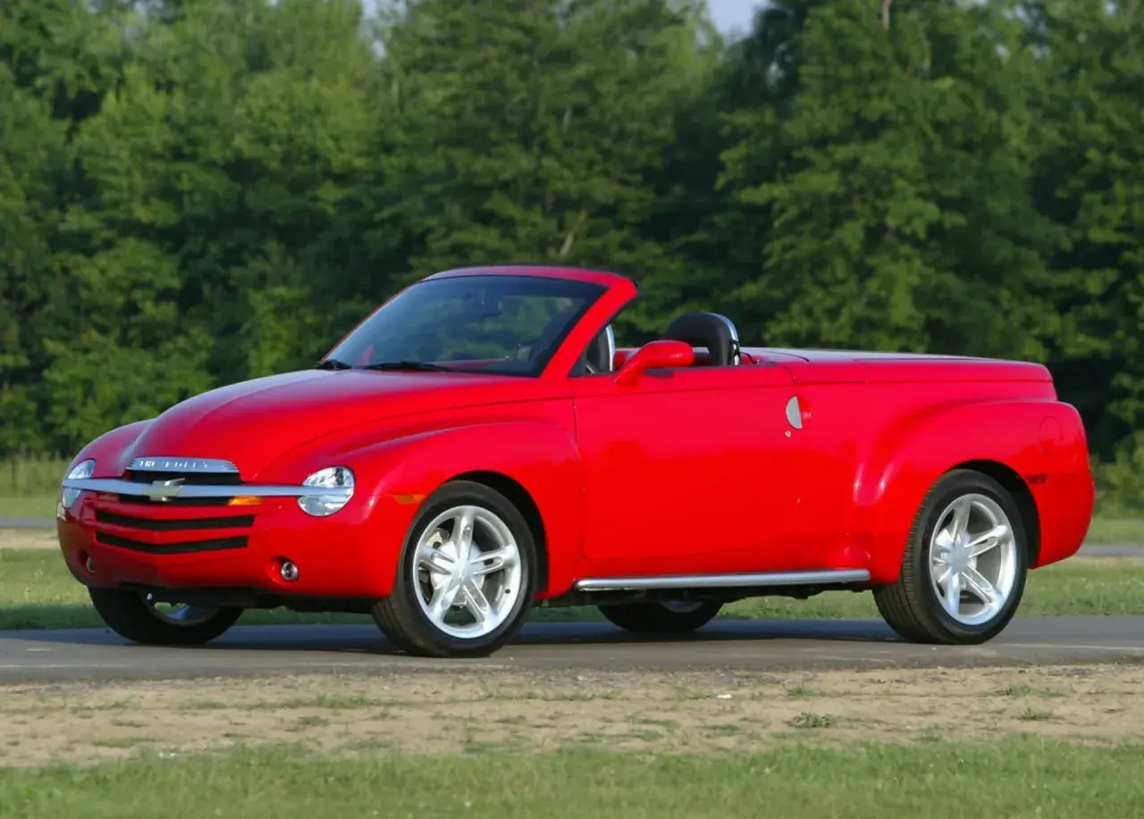 Czerwony Chevrolet SSR z otwartym dachem, gotowy na letnią przejażdżkę pośród zieleni.