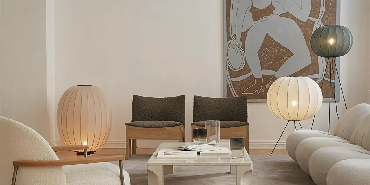 Un salón moderno con dos lámparas de pie grandes, una rosa y otra blanca, iluminando el espacio.