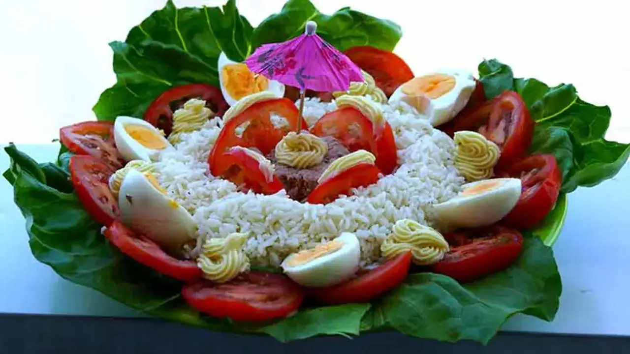 Salade de riz thon festive, garnie d'œufs durs, tomates, mayonnaise et d'un petit parasol rose. Un délice coloré !