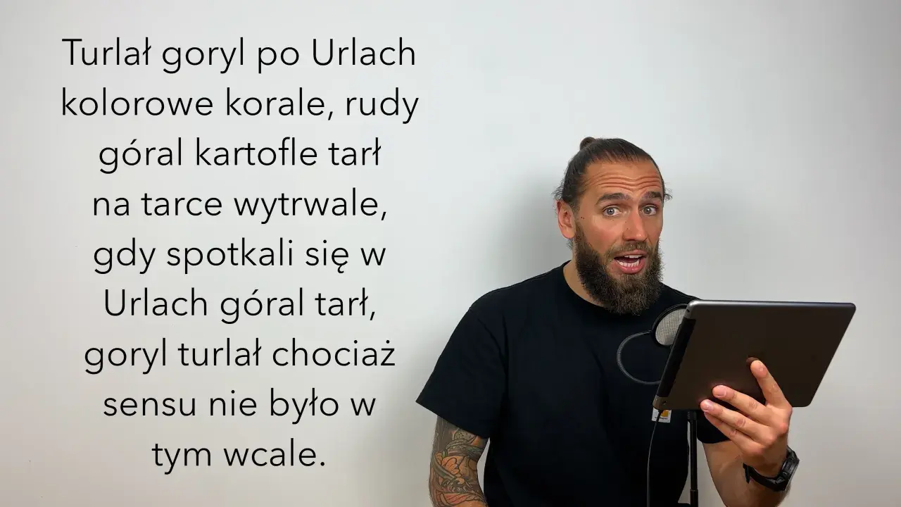 Mężczyzna z brodą i kitką czyta tekst o japońskich łamańcach językowych, gdzie goryl turlał się po Urlach, a góral tarł kartofle.