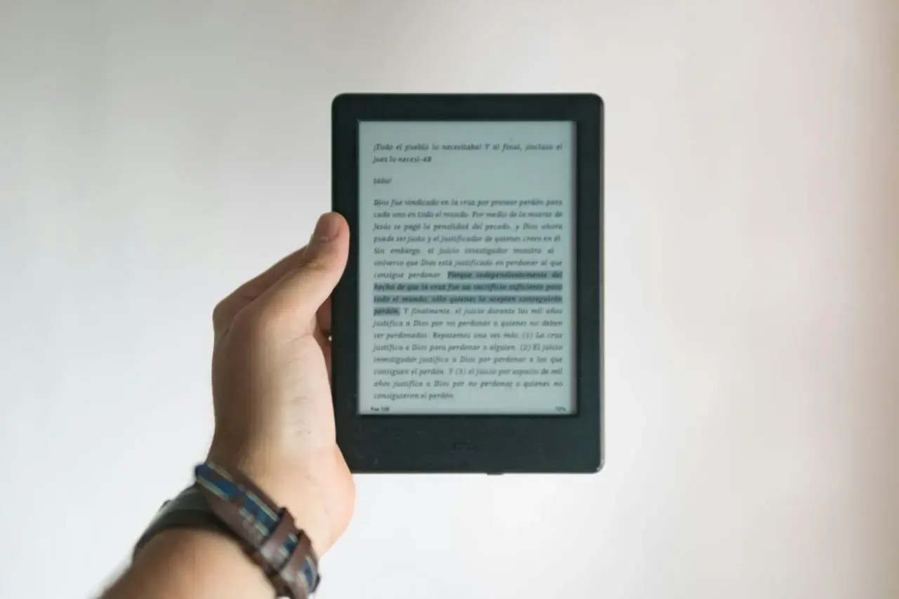 Dłoń trzyma czytnik e-booków. Tekst na ekranie dotyczy zasad ochrony praw autorskich przy wydawaniu e-booków.