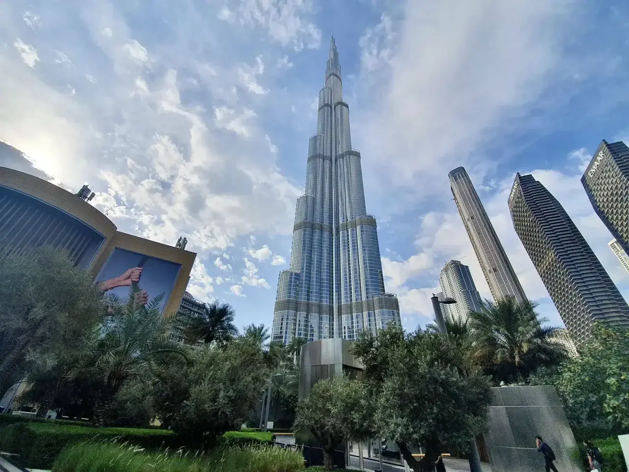 Majestatyczny Burj Khalifa w Dubaju wznosi się ku niebu, otoczony nowoczesnymi wieżowcami i zielenią.