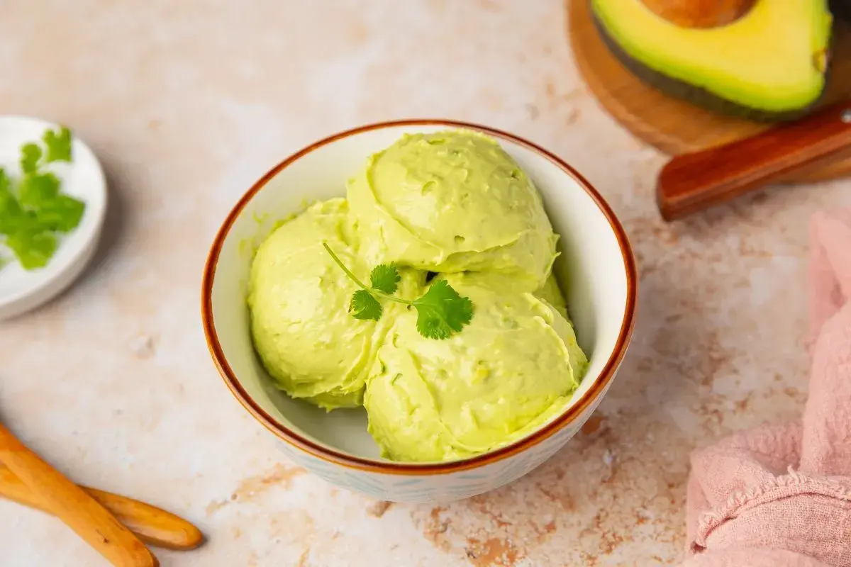 Un cremoso helado de aguacate, decorado con cilantro fresco, servido en un cuenco.