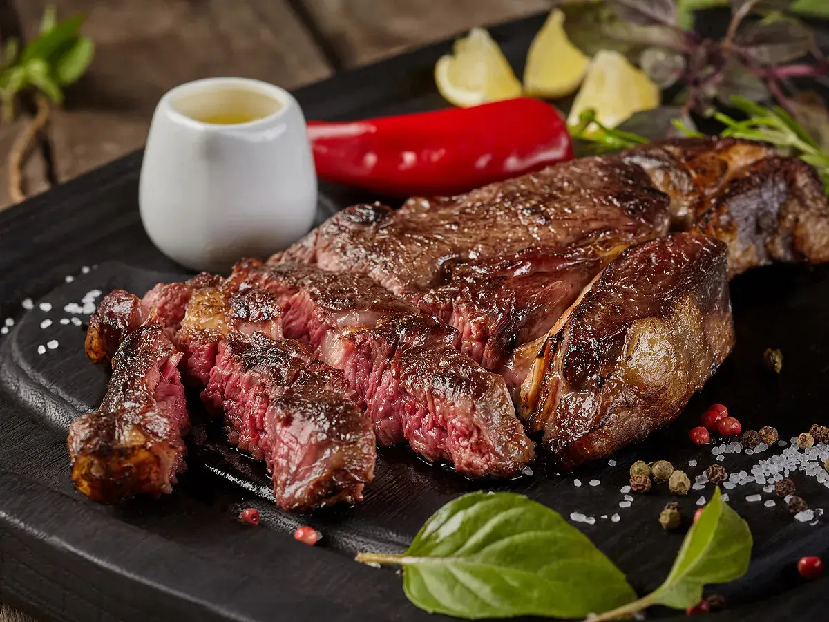 Une côte de bœuf parfaitement saisie, juteuse et rosée, prête pour la dégustation. La cuisson est idéale pour ce plat.
