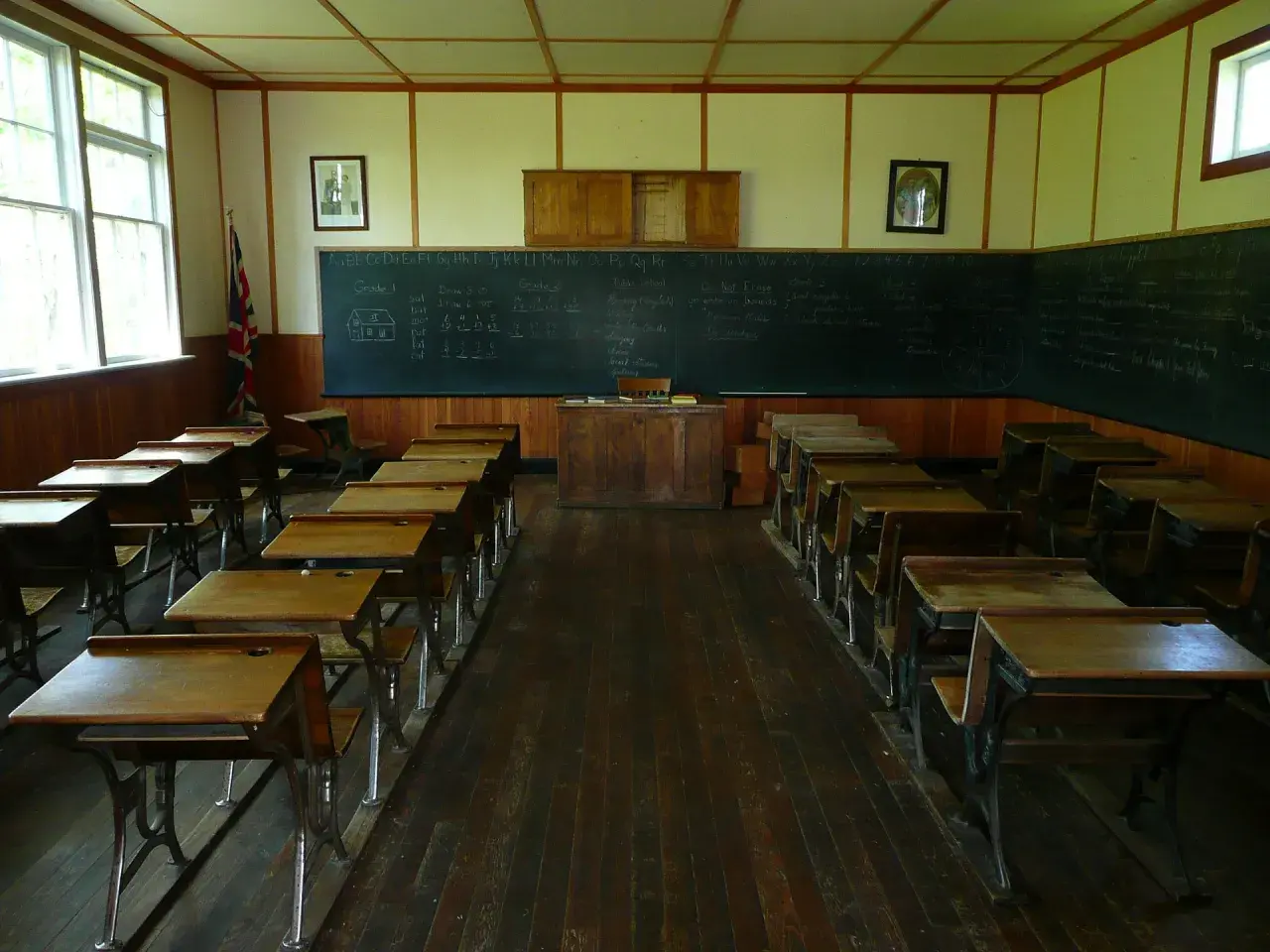 Klasa szkolna z ławkami i tablicą, gdzie widnieje statut szkoły.