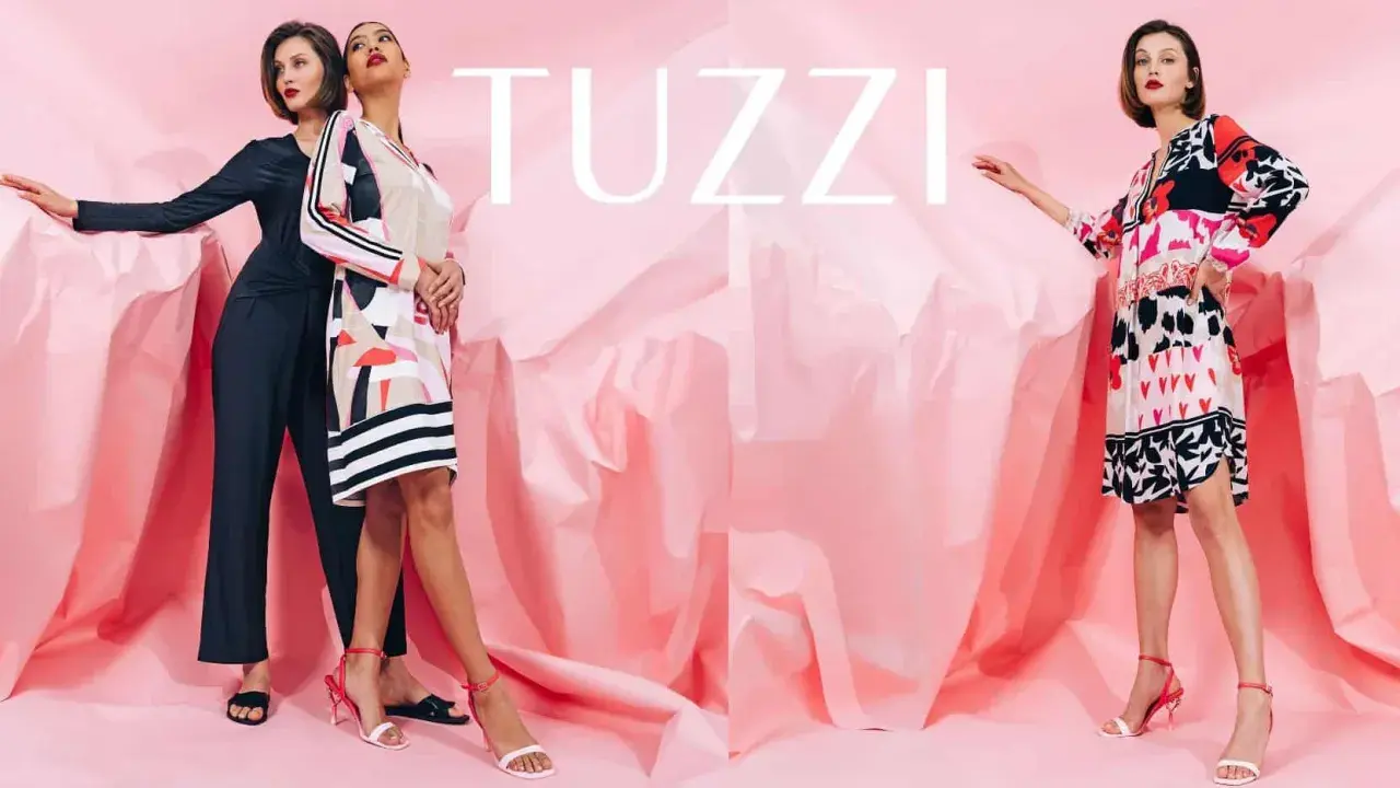 Eleganckie kobiety prezentują modne kreacje marki TUZZI na tle różowych, pofałdowanych tkanin.