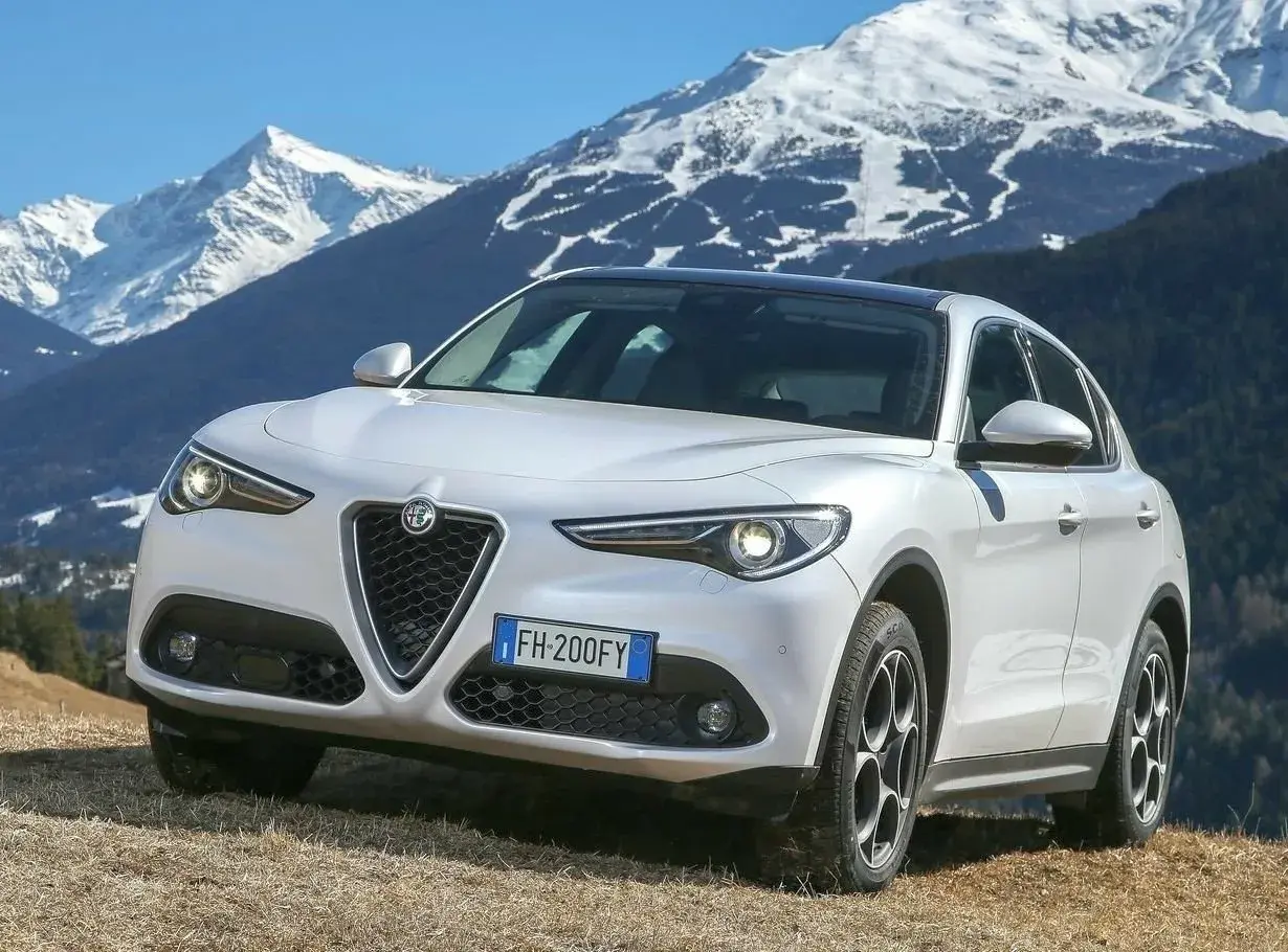 Białe Alfa Romeo Stelvio na tle ośnieżonych gór. Wiele pozytywnych alfa romeo stelvio opinie potwierdza jego wszechstronność.