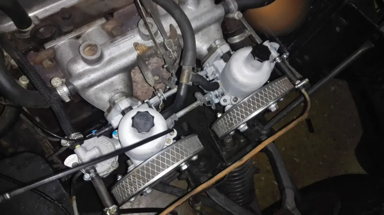 Detalle del motor de un coche clásico con doble carburador, listo para dar potencia.