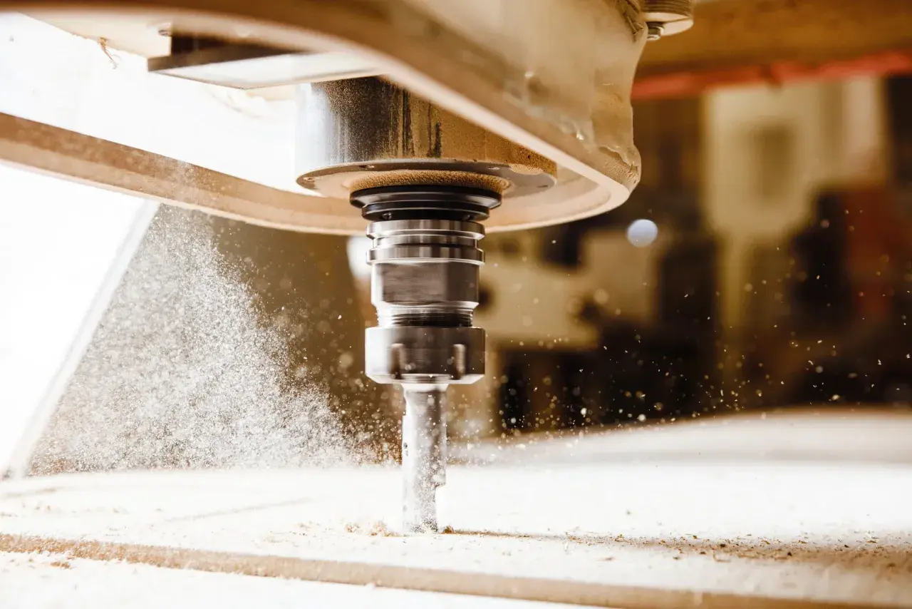 Precyzyjny frez CNC w akcji, tworzący drobny pył podczas obróbki drewna.