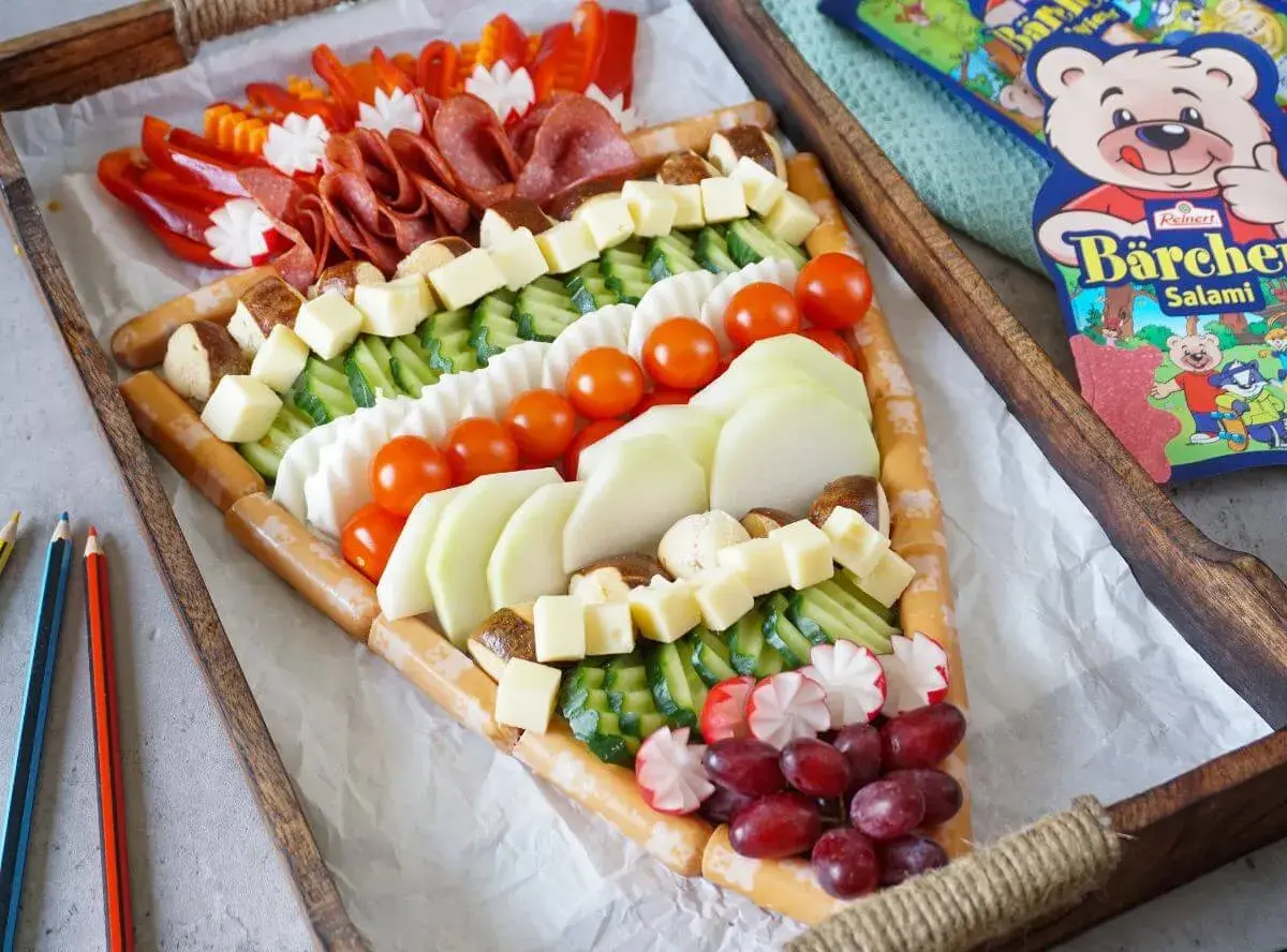 Ein kreatives Buffet für die Einschulung: Würstchen, Käse, Gemüse und Obst in einem tollen Muster arrangiert. Perfekt für eine Gartenparty!