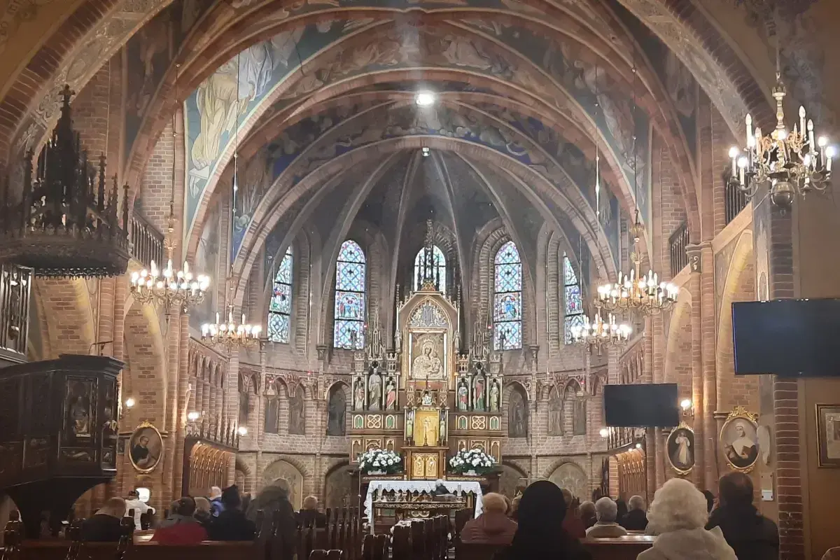 Wnętrze bazyliki z ołtarzem, gdzie króluje Matka Boska Gietrzwałdzka. Witraże i malowidła zdobią sklepienie.