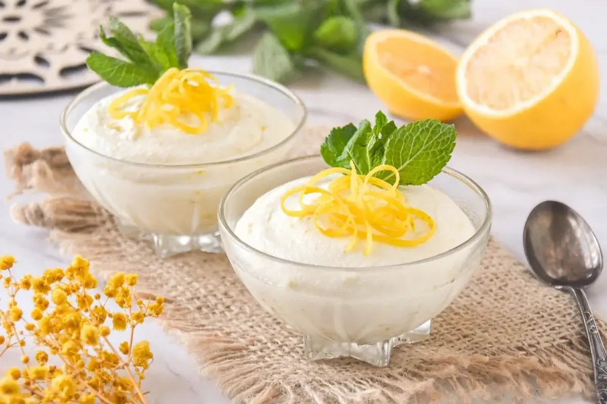 Delicioso mousse de limón con leche condensada, adornado con ralladura de limón y menta fresca.
