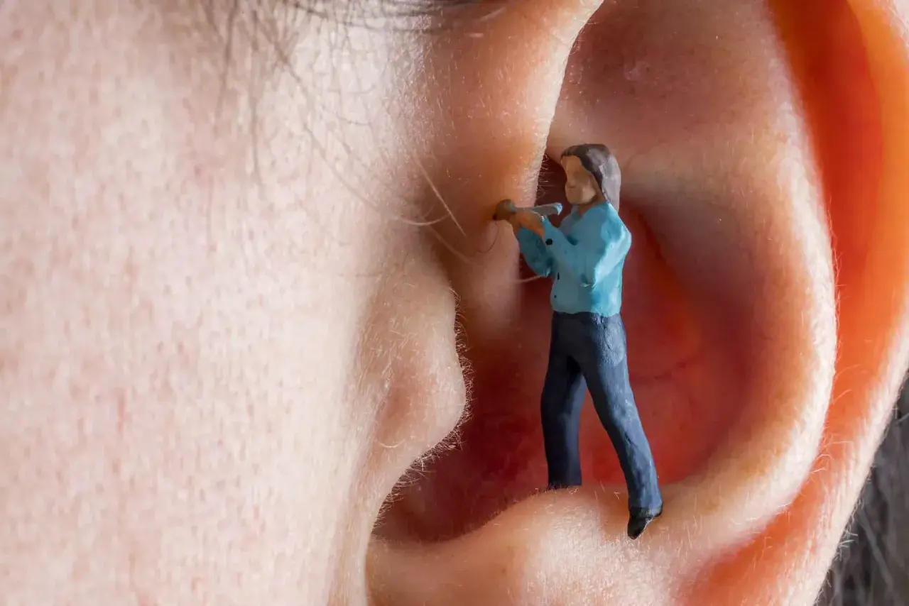 Kleine Figur im Ohr, die versucht, den Tinnitus zu bekämpfen. Vitamin B12 könnte helfen.
