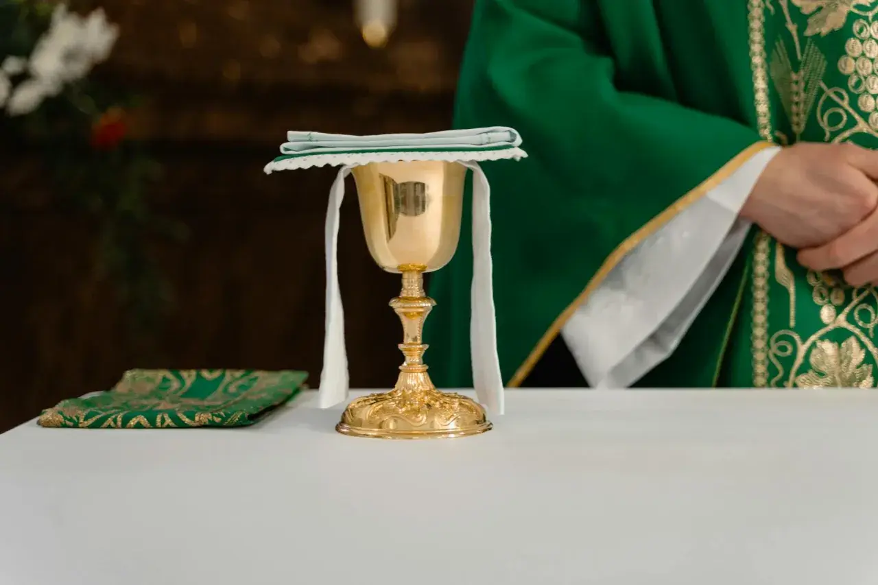 Złoty kielich i zielona stuła kapłana podczas post eucharystyczny.