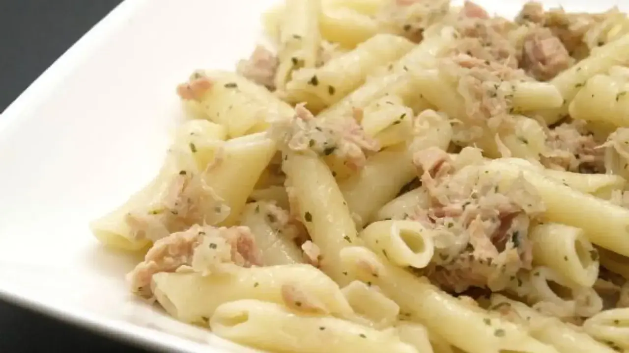 Macarrones con atún, un plato sencillo y delicioso. Pasta penne mezclada con atún desmenuzado y hierbas verdes.