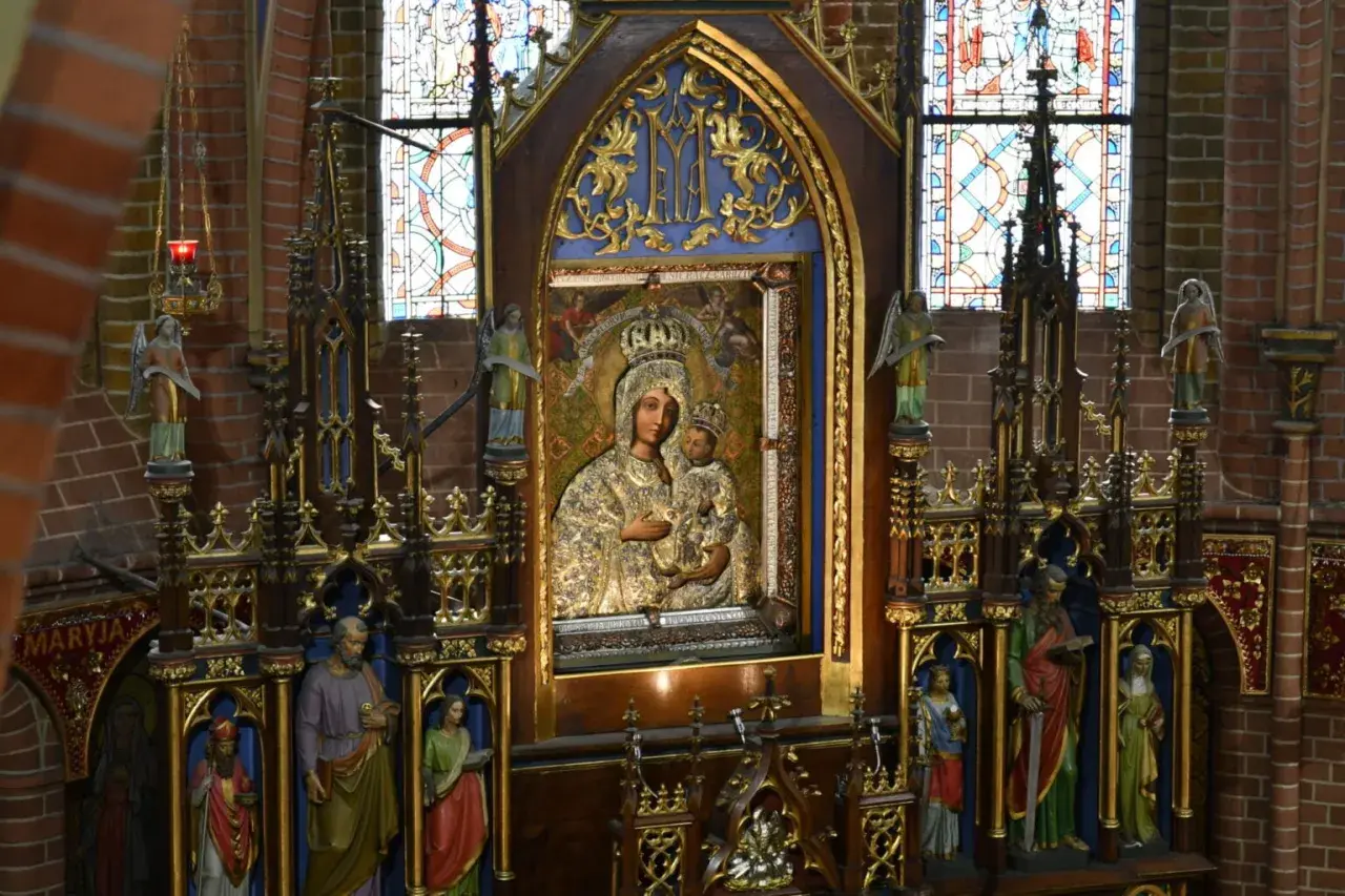 Ołtarz z obrazem Matki Boskiej, symbol objawień maryjnych w Polsce. Witraże i rzeźby dopełniają sakralny wystrój.