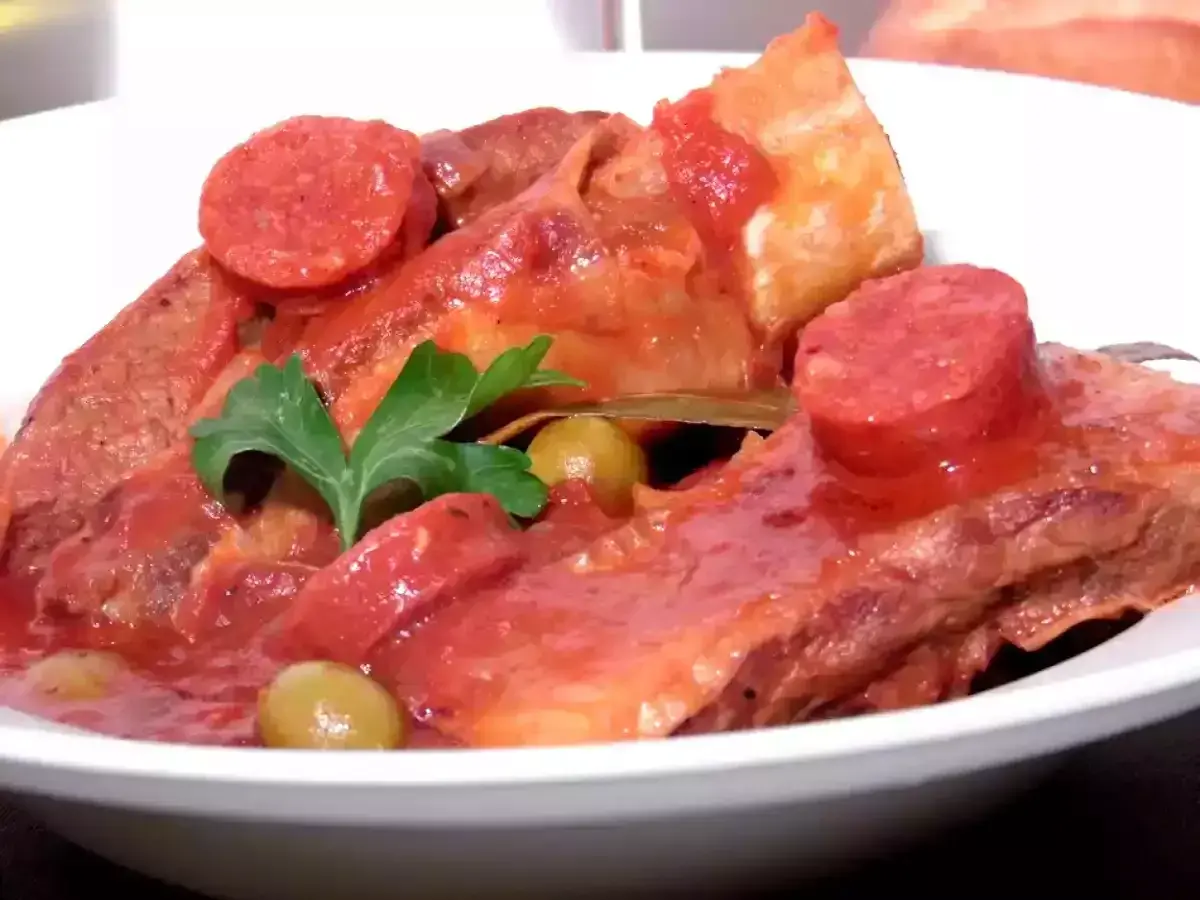 Un plat savoureux de tendron de veau mijoté dans une sauce tomate, garni de rondelles de chorizo, d'olives et d'une touche de persil.