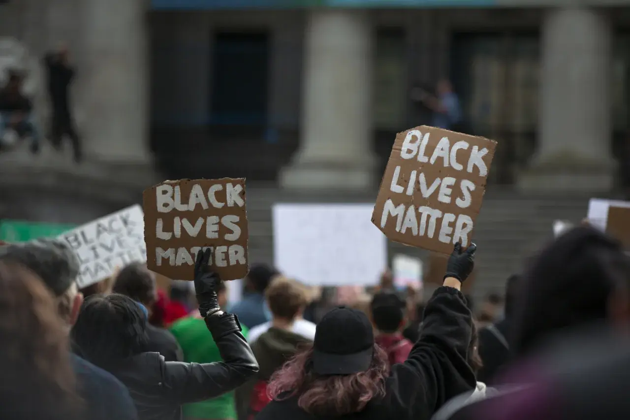 Ludzie protestują przeciwko rasizmowi, trzymając transparenty "Black Lives Matter".