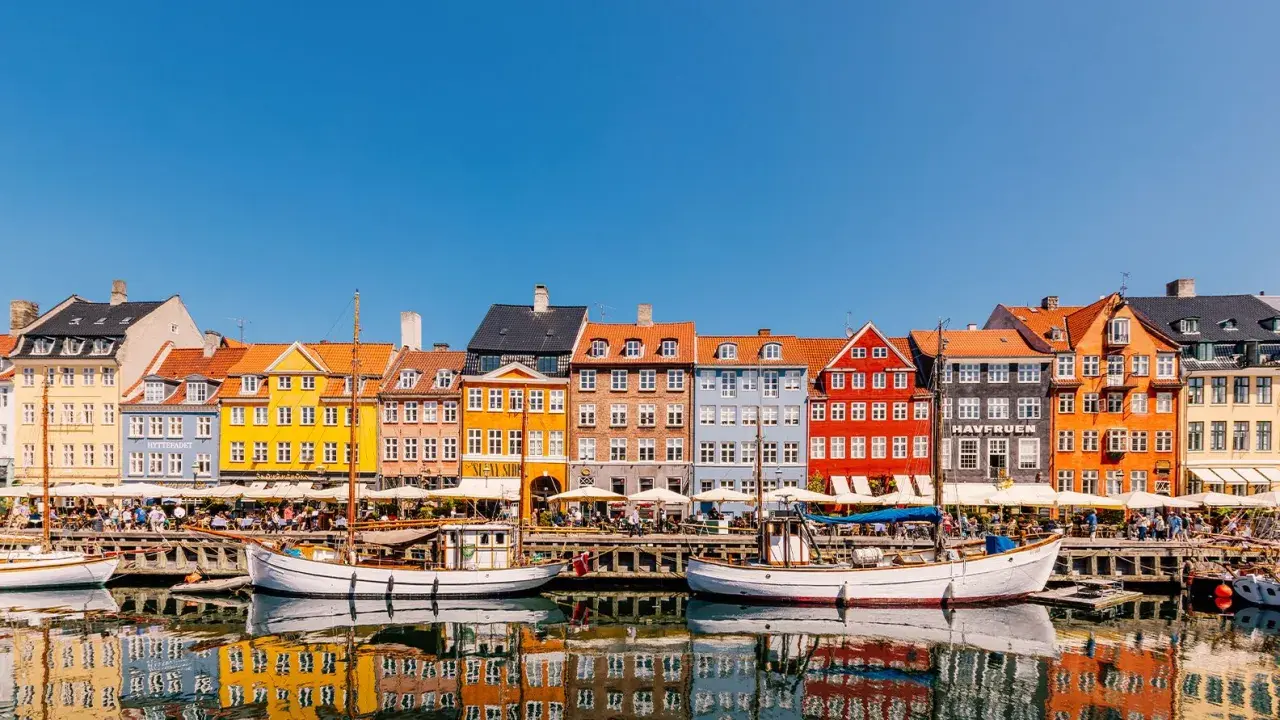 Bunte Häuser am Nyhavn, ein Kopenhagen must see. Boote spiegeln sich im Wasser.