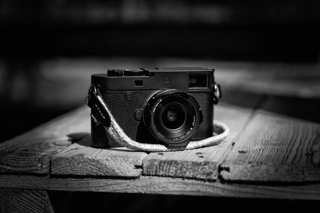 Klasyczny aparat Leica M10 Monochrom z obiektywem na drewnianym blacie.