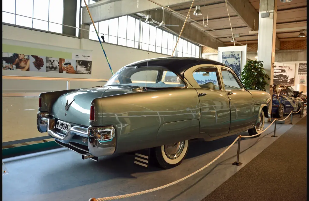 A vintage Volvo sedan, light green with a dark roof, is displayed indoors.
