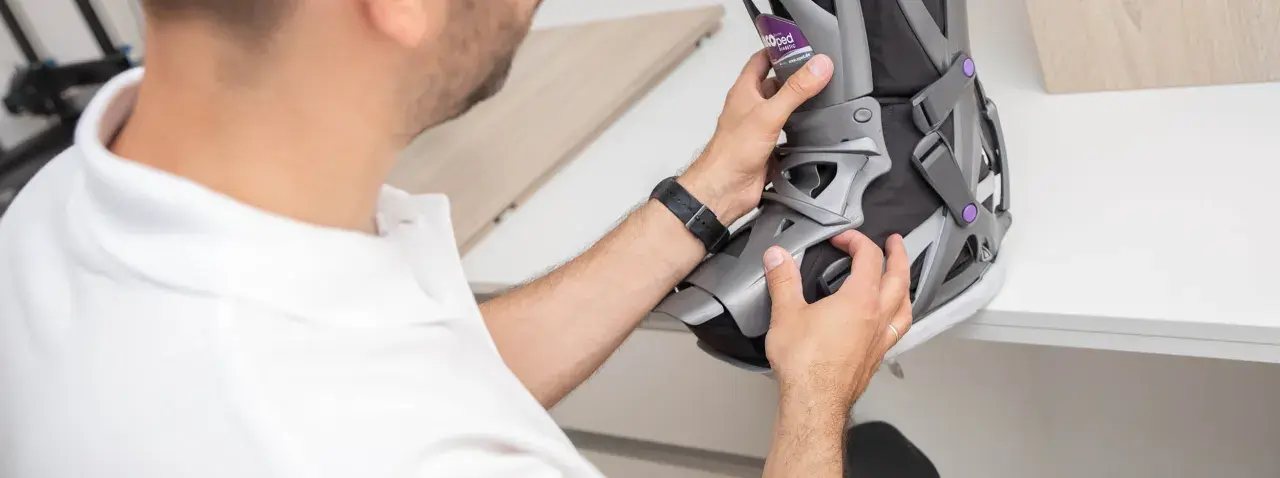 Mann mit weißem Poloshirt passt eine orthopädische Schiene an, die auf einem Rezept für orthopädische Schuhe basiert.