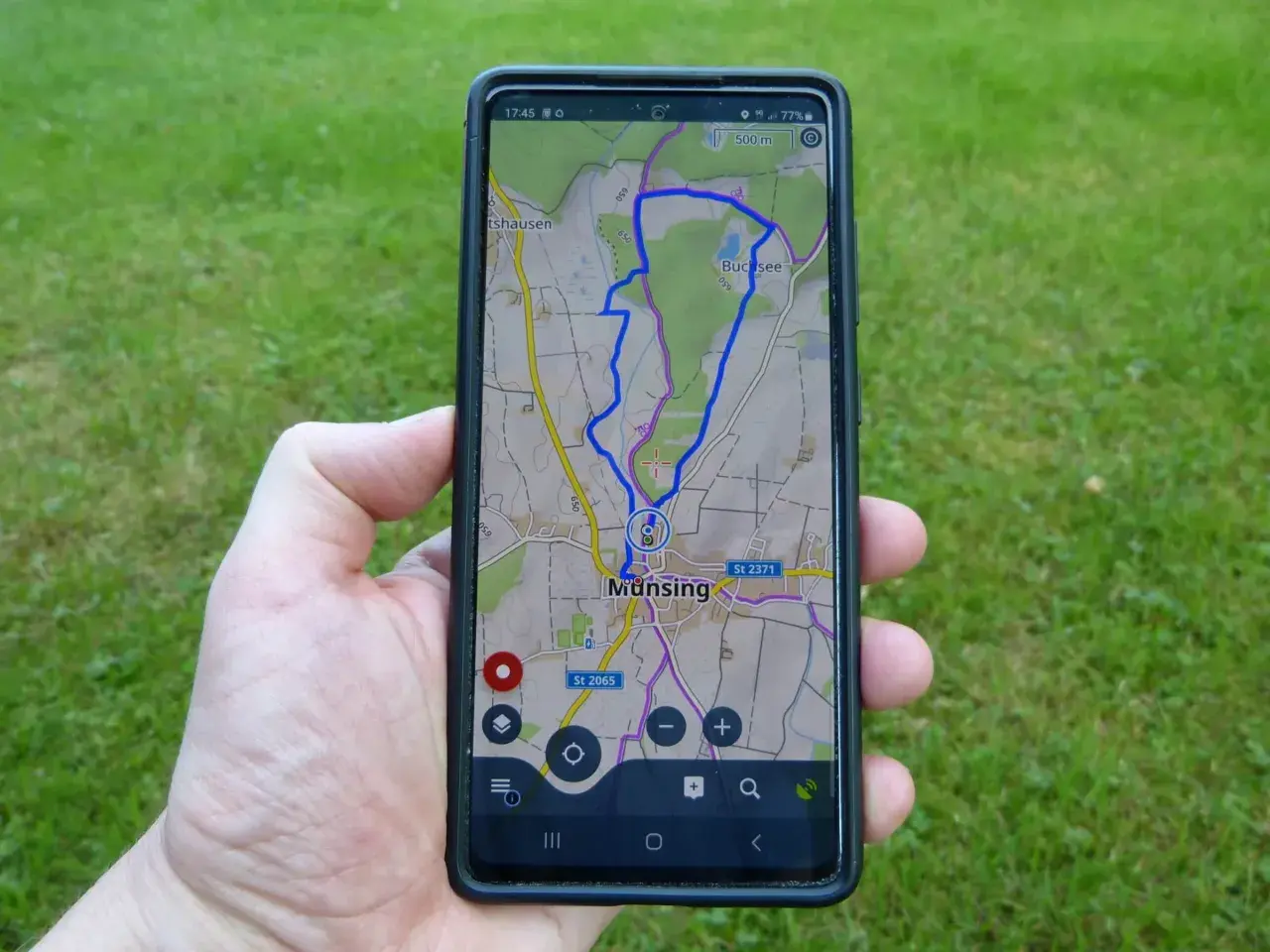 Hand hält Smartphone mit einer Wanderwege App, die eine Route bei Munsing anzeigt. Perfekt für die nächste Tour!