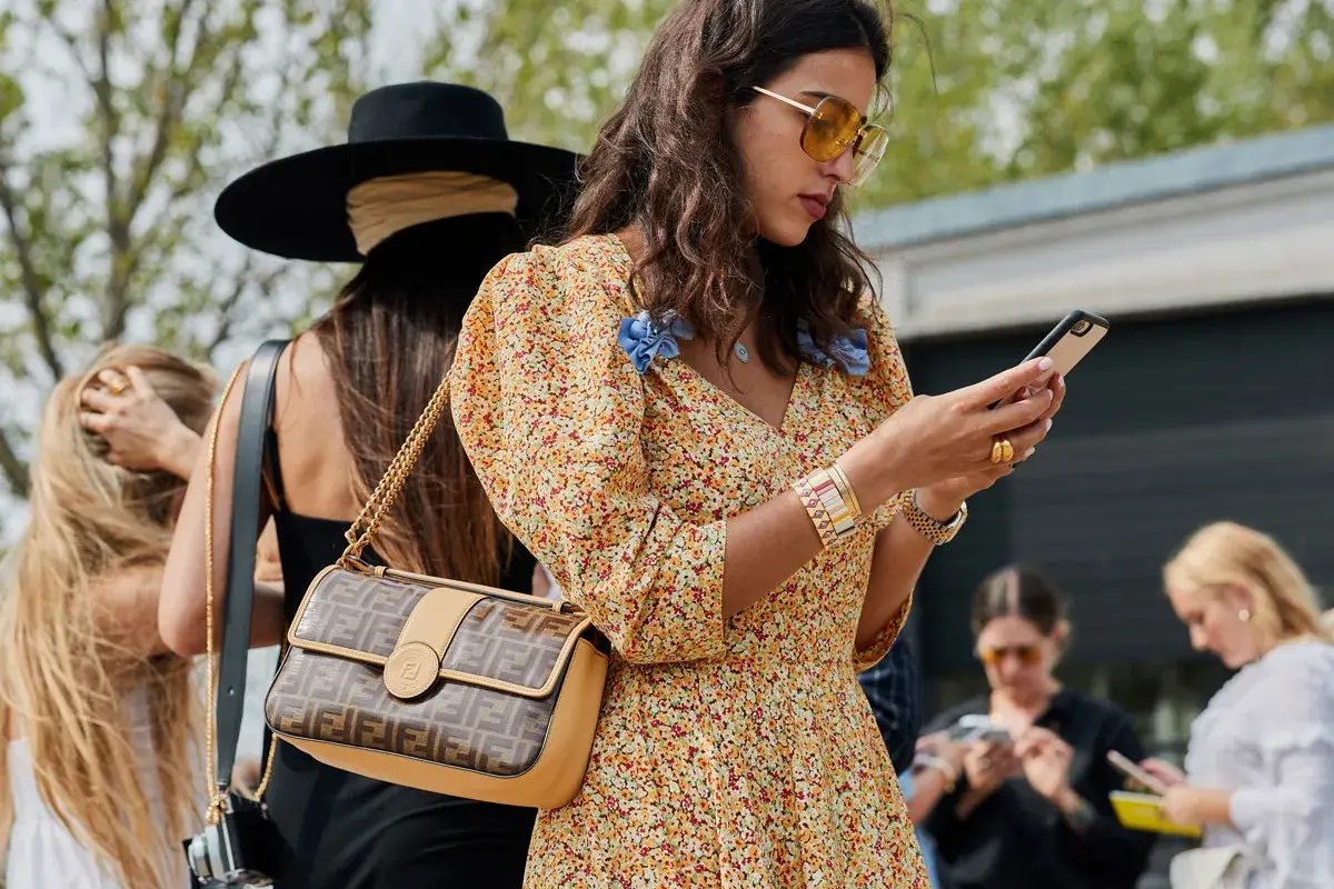 Kobieta w kwiecistej sukience i okularach przeciwsłonecznych, z torebką Fendi, uosabia styl boho moda.