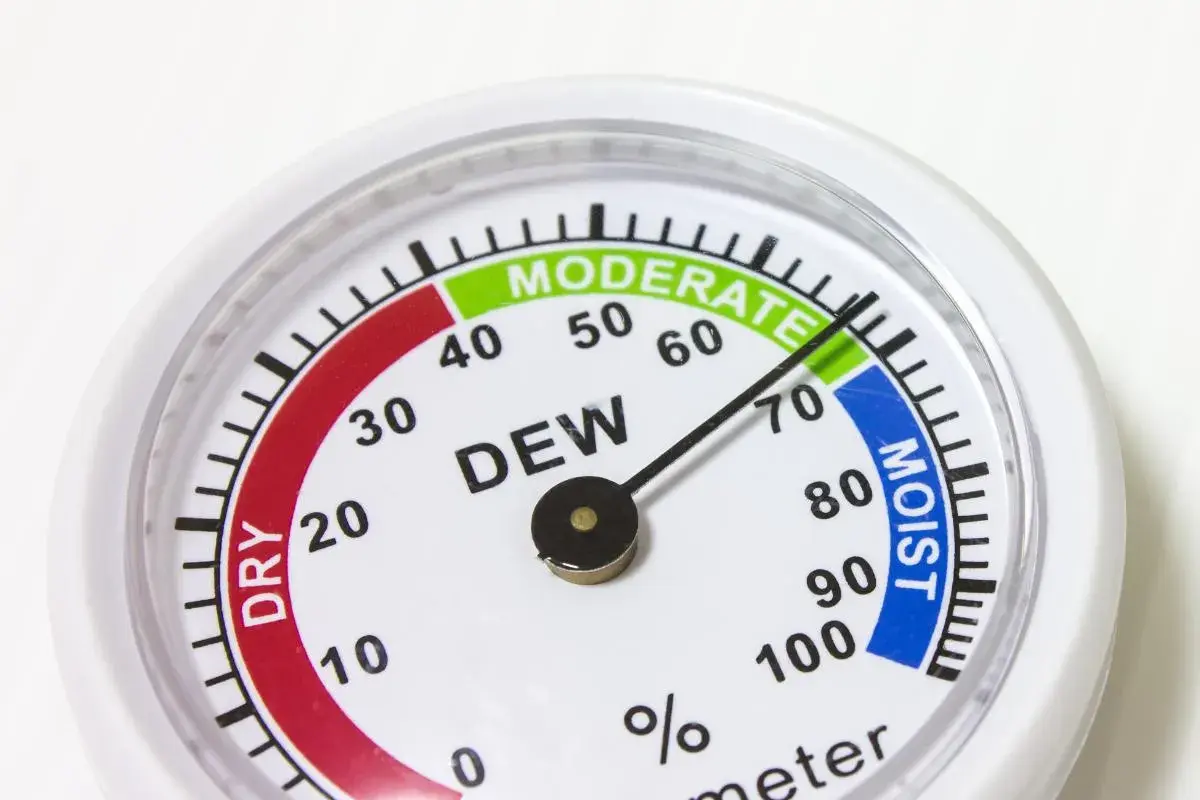 Un higrómetro que mide la humedad del aire, con zonas indicadas como "DRY", "MODERATE" y "MOIST".