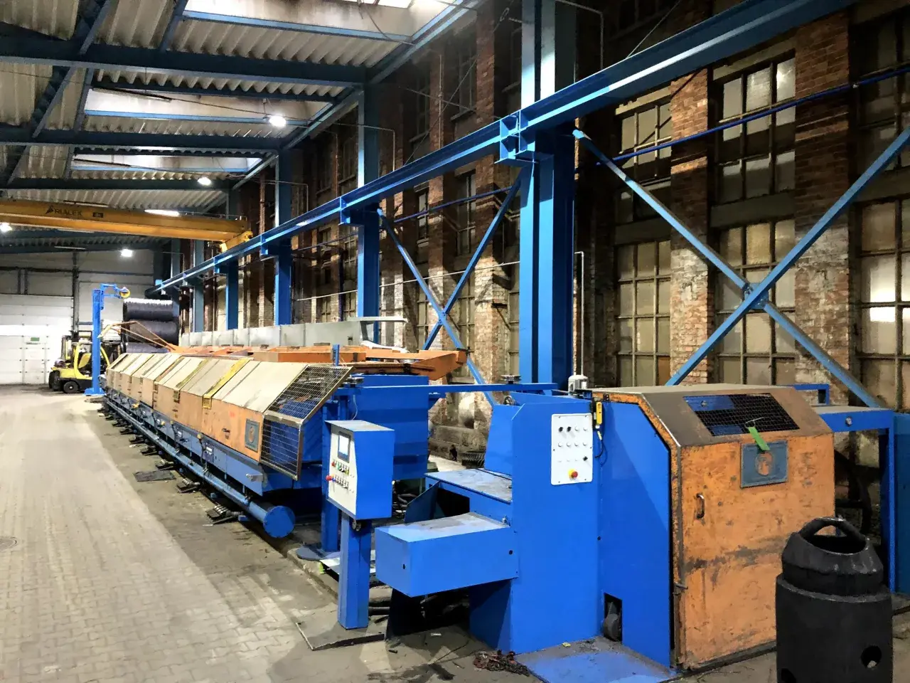 Linia produkcyjna w hali przemysłowej, z widocznym sterowaniem i elementami automatyki. To idealne miejsce na poradnik automatyka.