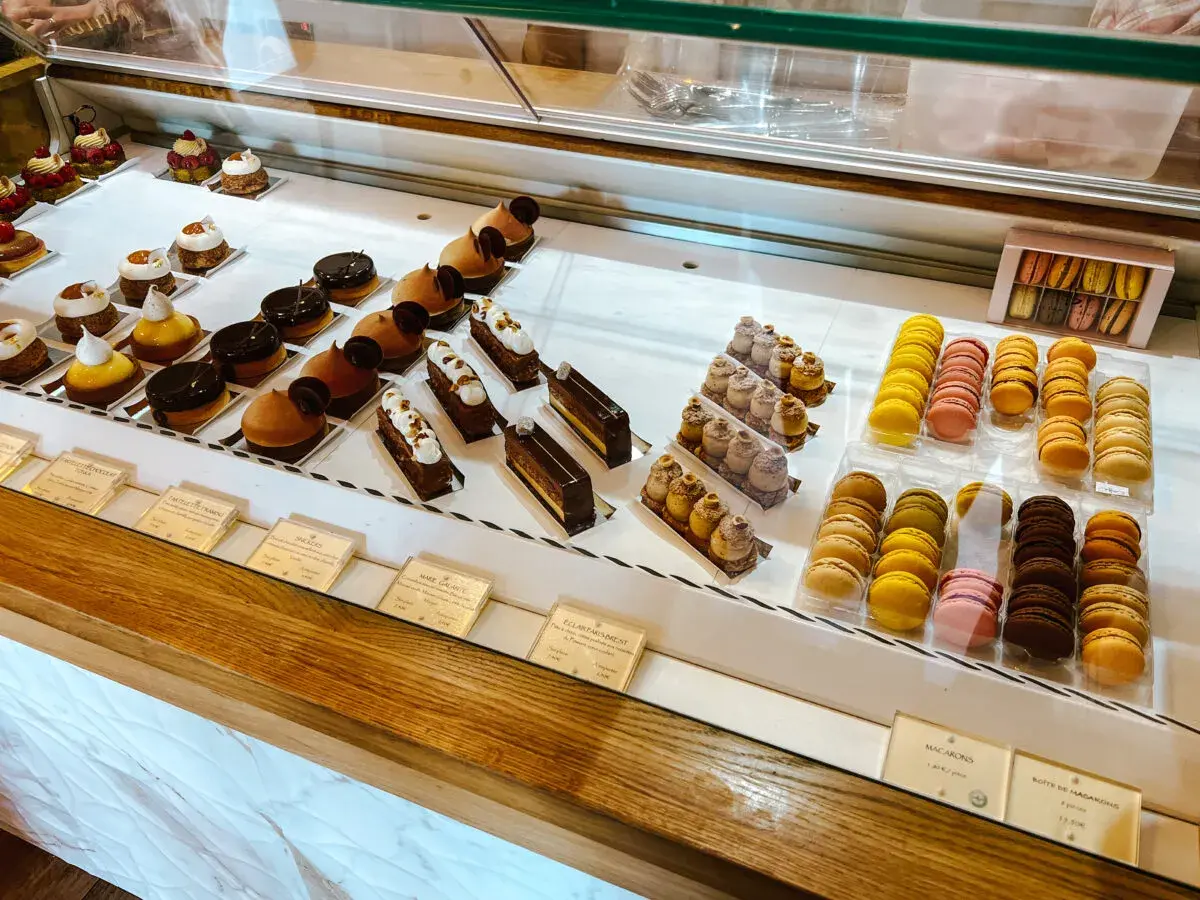 Witryna cukierni z wykwintnymi deserami, w tym makaronikami i ciastkami, idealna dla szukających najlepszych francuskich restauracji.