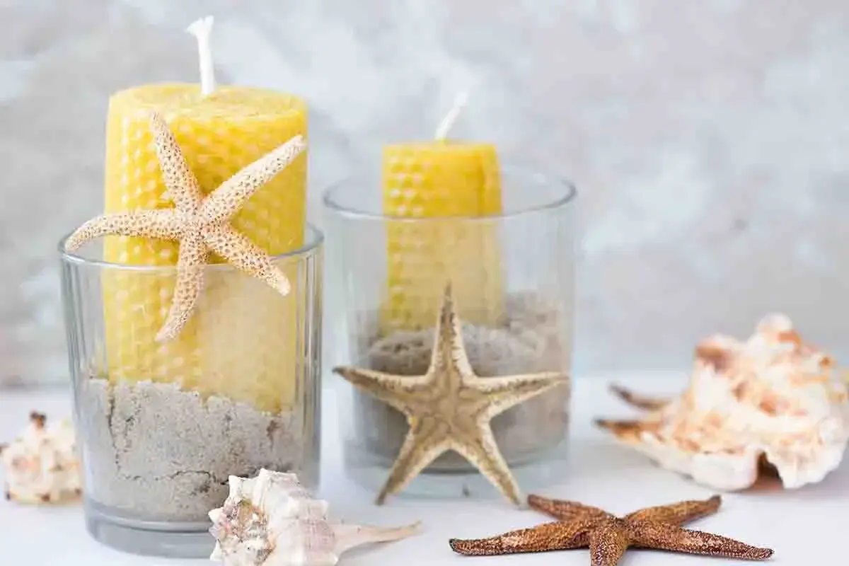 Candelabri fai da te con candele gialle, sabbia e stelle marine in bicchieri di vetro. Un tocco marino per la tua casa.