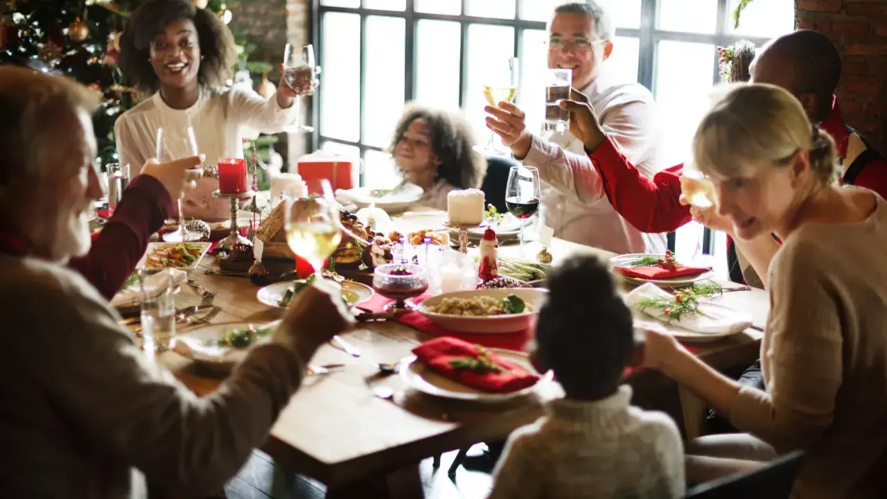 Familie feiert Weihnachten am festlich gedeckten Tisch. Alle stoßen an, die Stimmung ist fröhlich. Das ist die beste Weihnachtsrede!