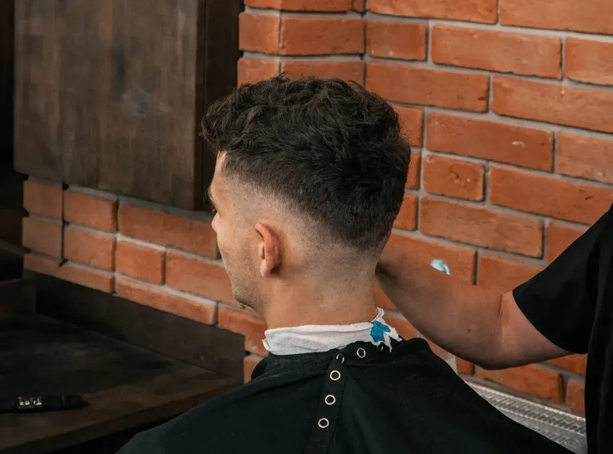 Mężczyzna z modną fryzurą fade, której nadano objętość za pomocą prestyler do włosów.
