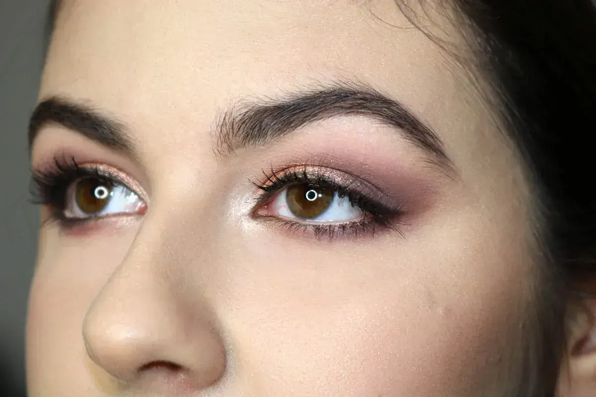 Occhi marroni con makeup sfumato sui toni del rosa e del bronzo, che ne esaltano la forma. Ciglia lunghe e folte.