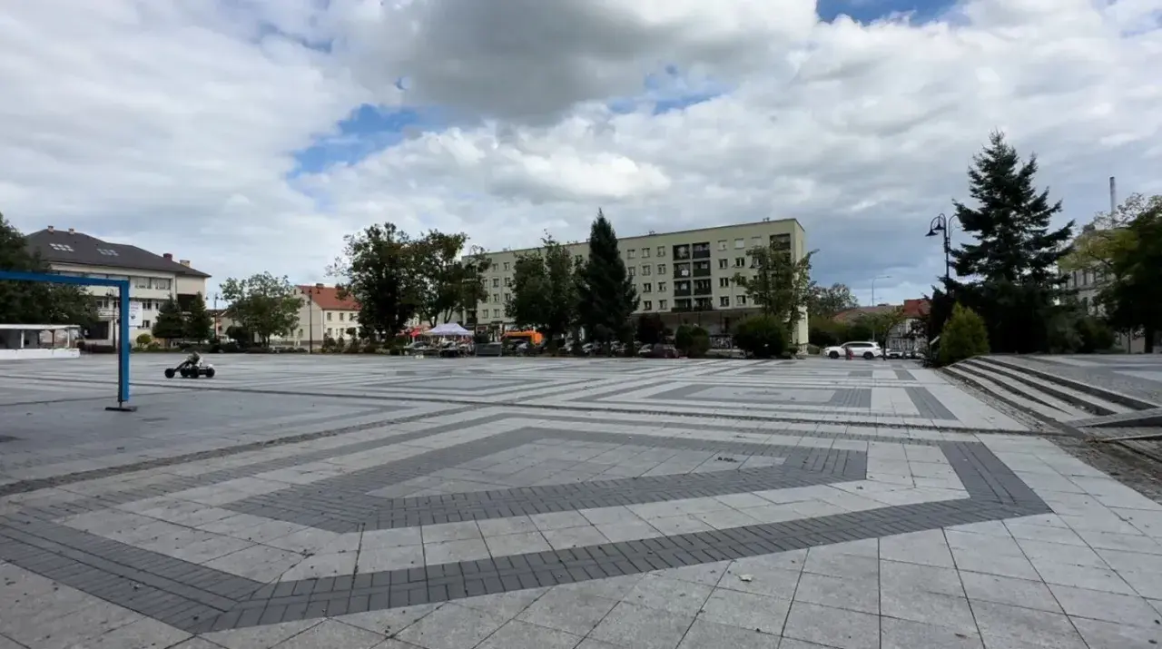 Dziecko śmiga gokartem po pustym, największym rynku w Polsce. W tle budynki i drzewa.