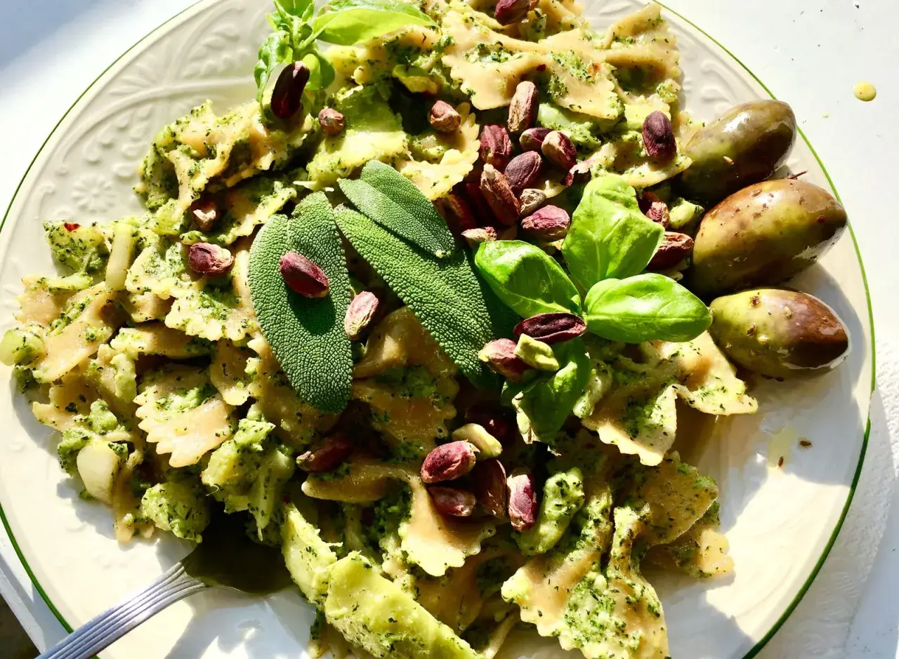 Farfalle condite con un saporito pesto di salvia, pistacchi e basilico fresco, guarnite con olive verdi.
