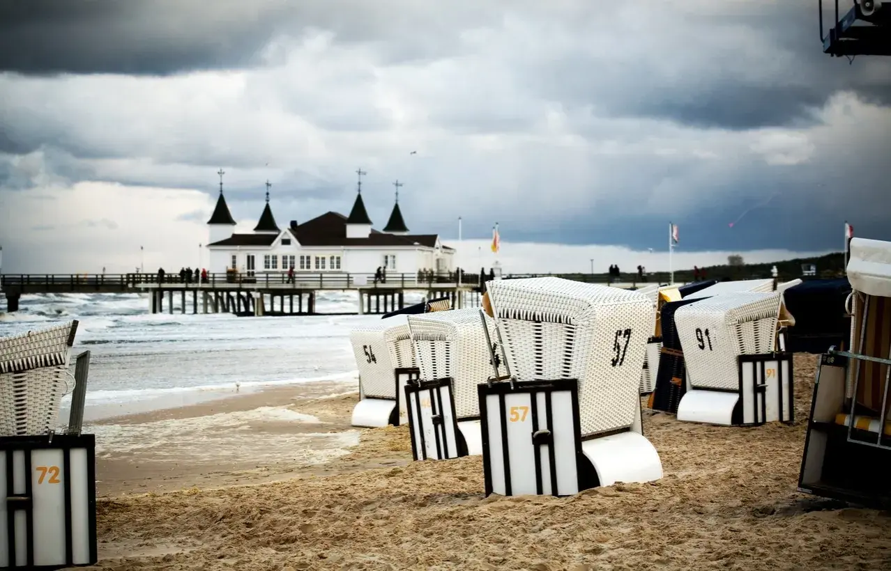 Strandkörbe am Ostseestrand mit Pier und Gebäude im Hintergrund. Perfekte ausflugsziele ostsee bei schlechtem wetter, um dem Wind zu trotzen.
