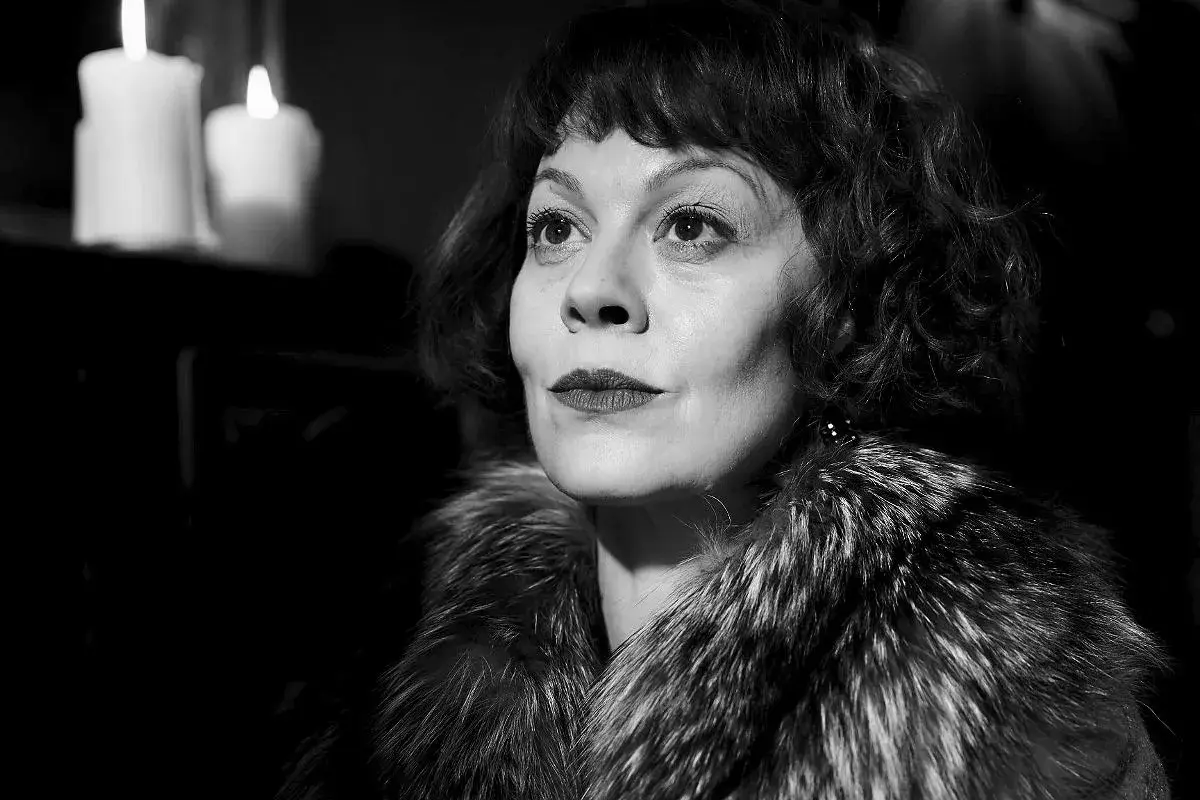 Helen McCrory, znana z roli Narcyzy Malfoy w Harry Potter, w eleganckim futrze i przy świecach.
