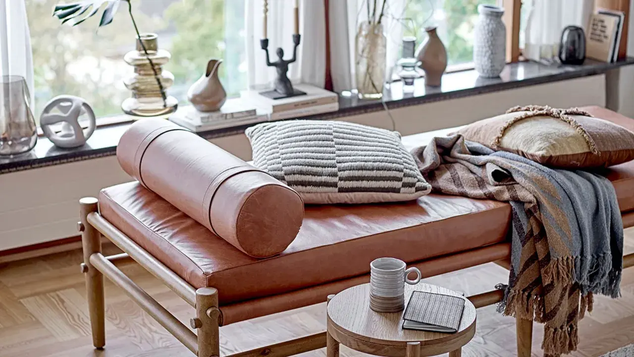 Un cómodo espacio de meditación con un banco de cuero, cojines texturizados y mantas cálidas.