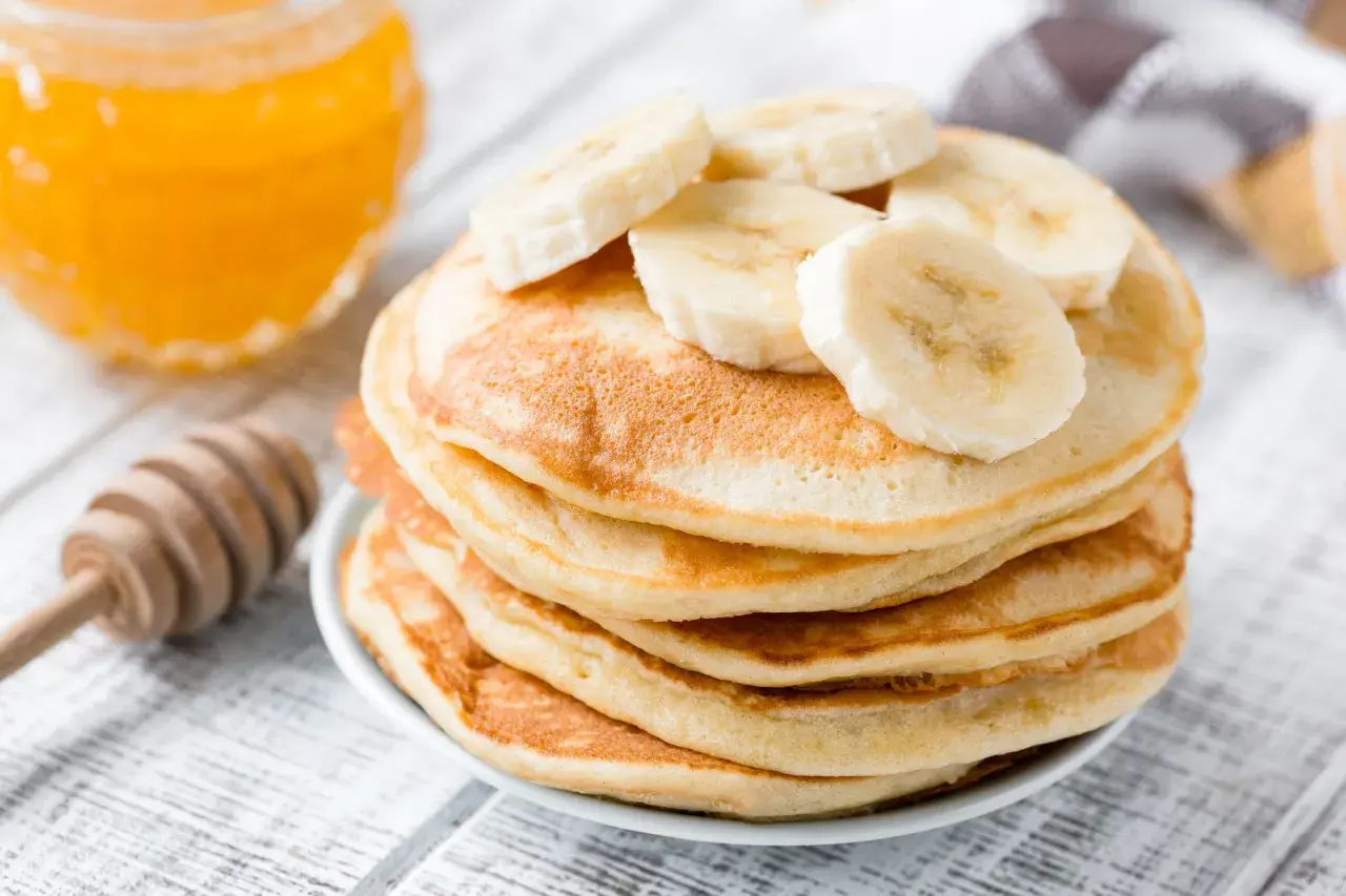 Pancake perfetti, dorati e soffici, preparati con la friggitrice ad aria, guarniti con fette di banana e miele.