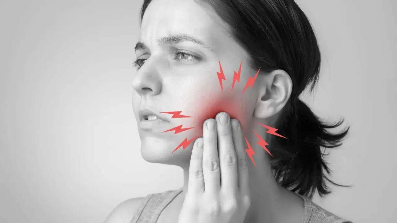 Mujer con dolor de muelas, tocándose la mejilla. Rayos rojos indican el dolor. ¿Qué hacer para el dolor de muelas?