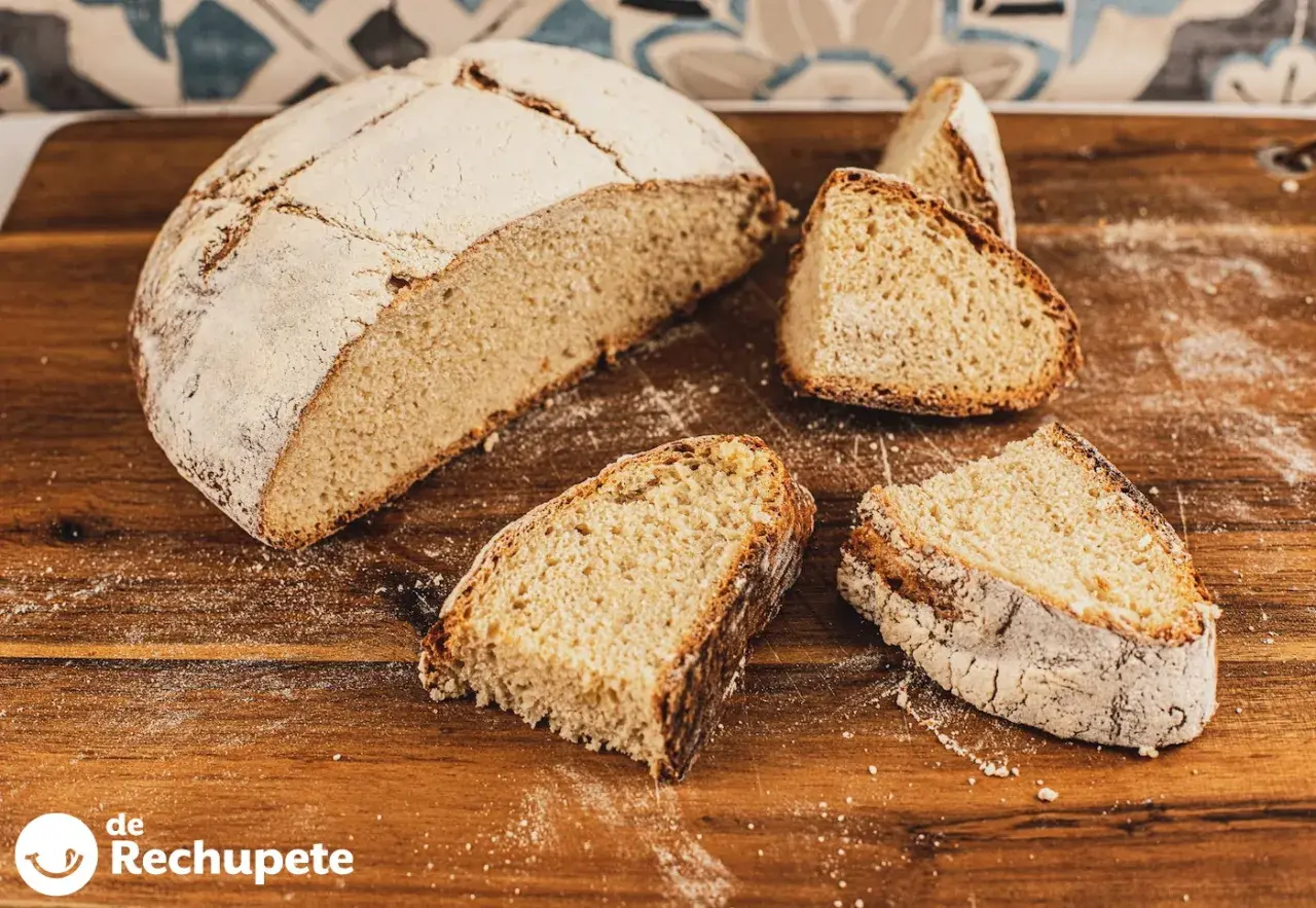 Un pan de papa casero, con su corteza dorada y miga esponjosa, cortado en rebanadas sobre una tabla de madera.